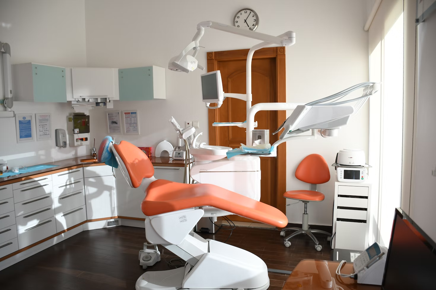 An empty chair in a dental office, surrounded by equipment.